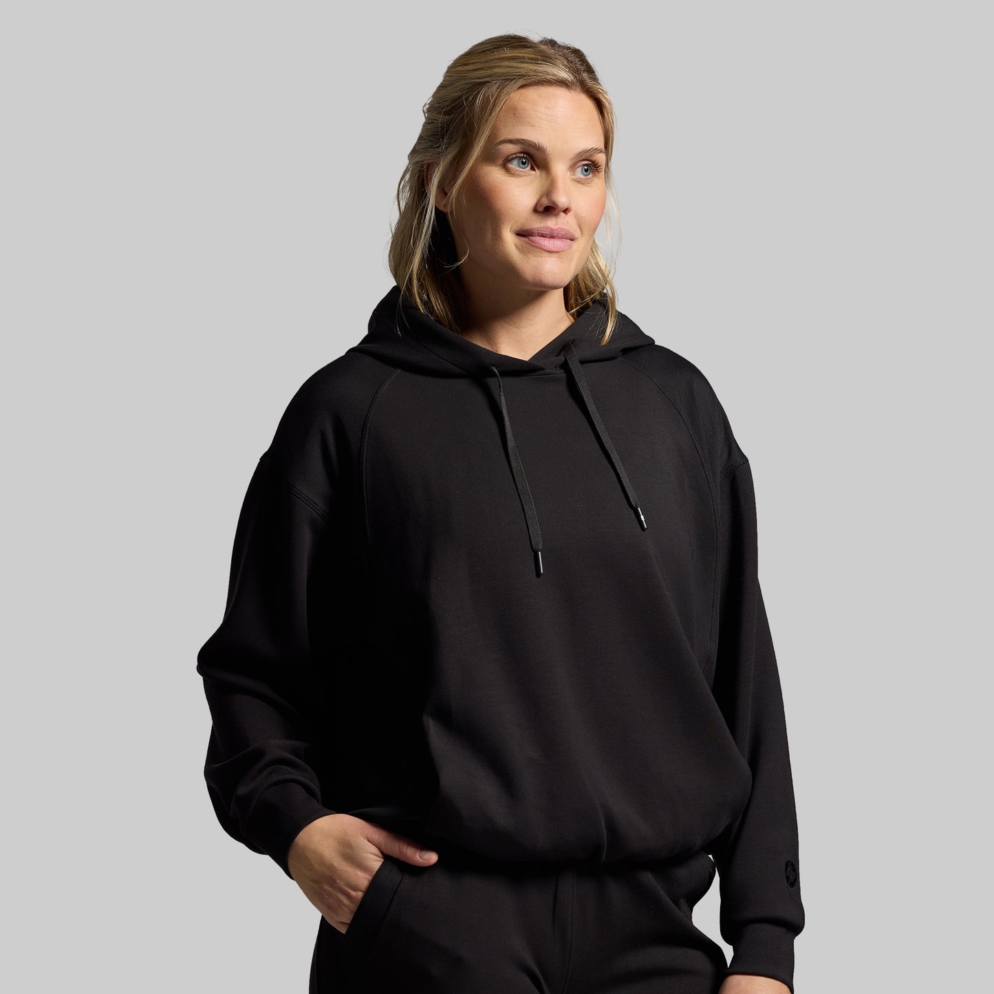 Woman wearing a black hoodie against a plain background