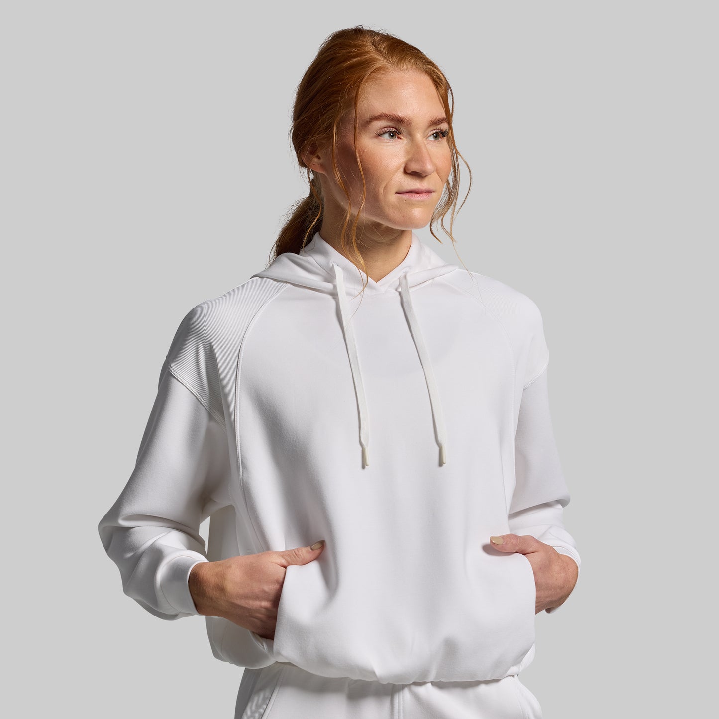 Person wearing a white hoodie against a plain background