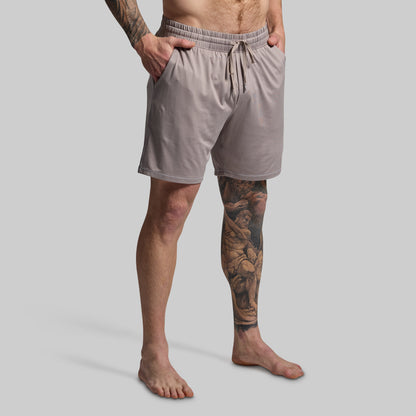 Man wearing light gray shorts on a plain background