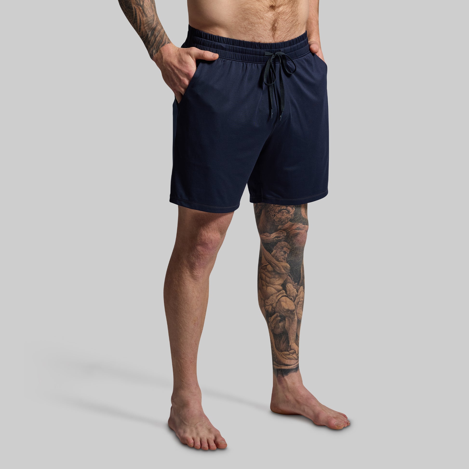 Person wearing navy blue shorts on a gray background