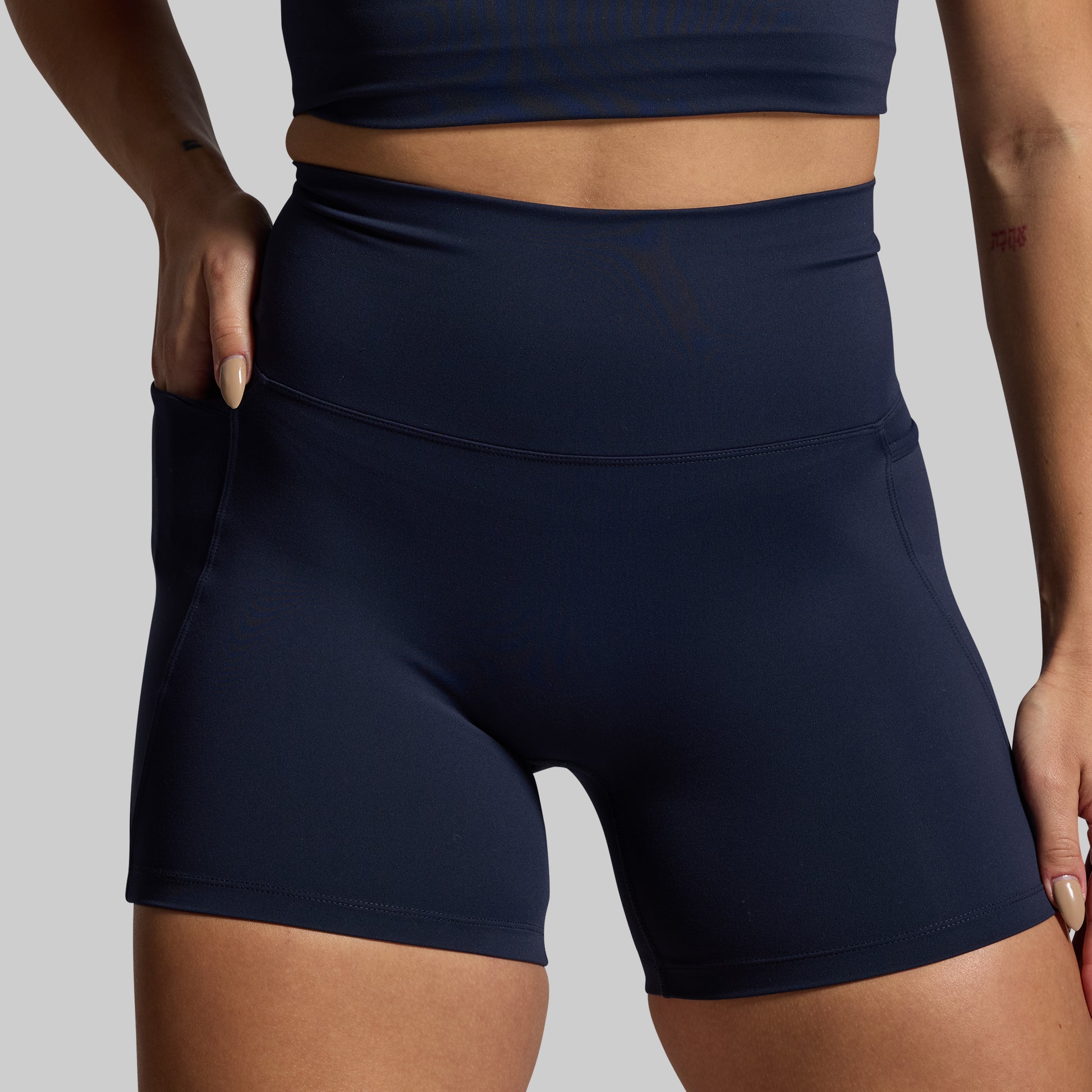 Navy blue athletic shorts worn by a person on a gray background