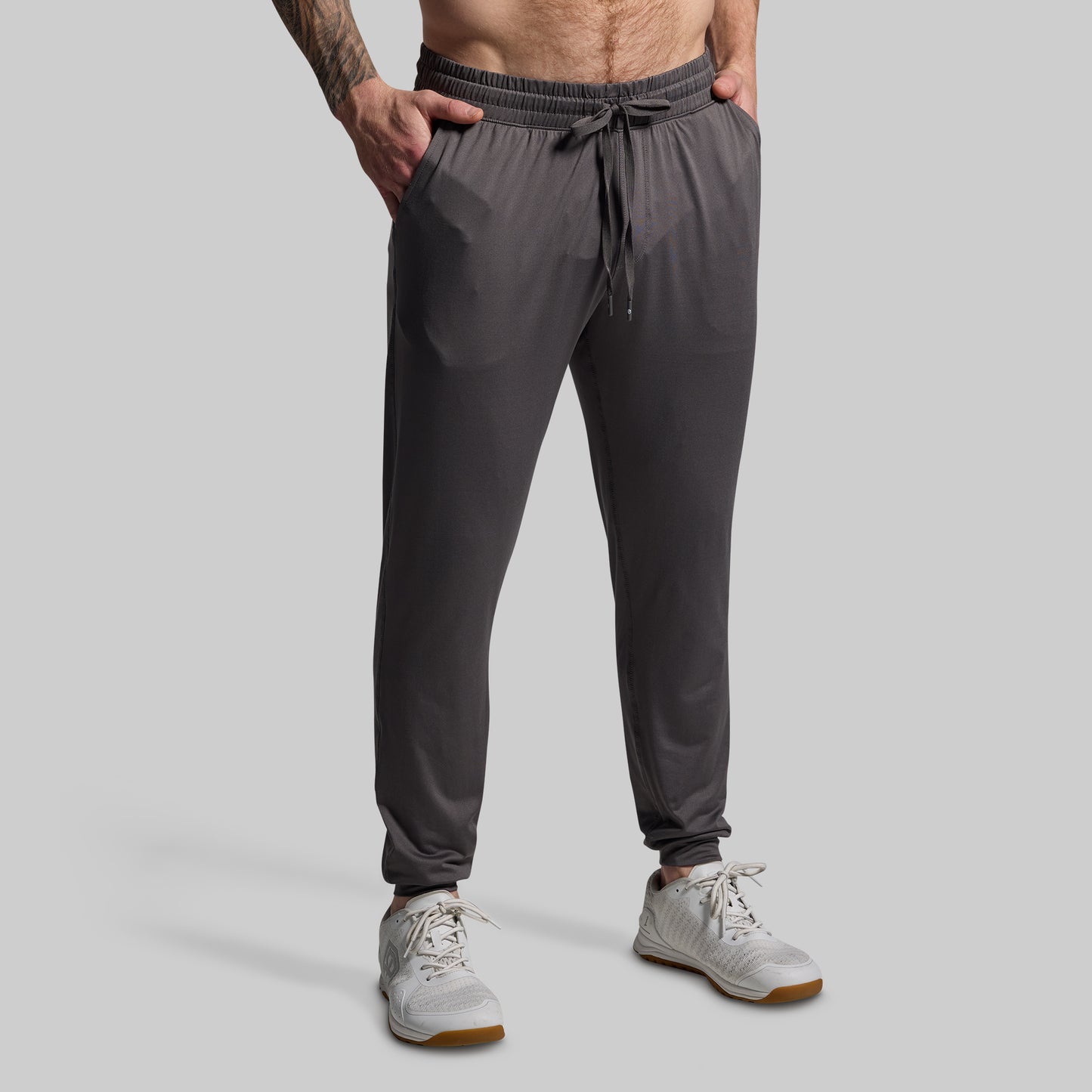 Person wearing gray jogger pants on a plain background