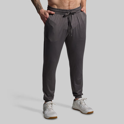 Person wearing gray jogger pants on a plain background