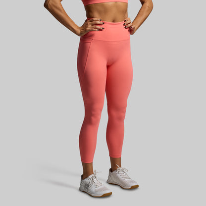 Person wearing coral leggings and a sports bra on a gray background