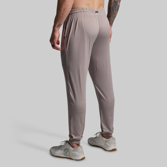 Person wearing gray jogger pants on a gray background