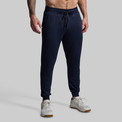 Person wearing navy blue jogger pants on a gray background