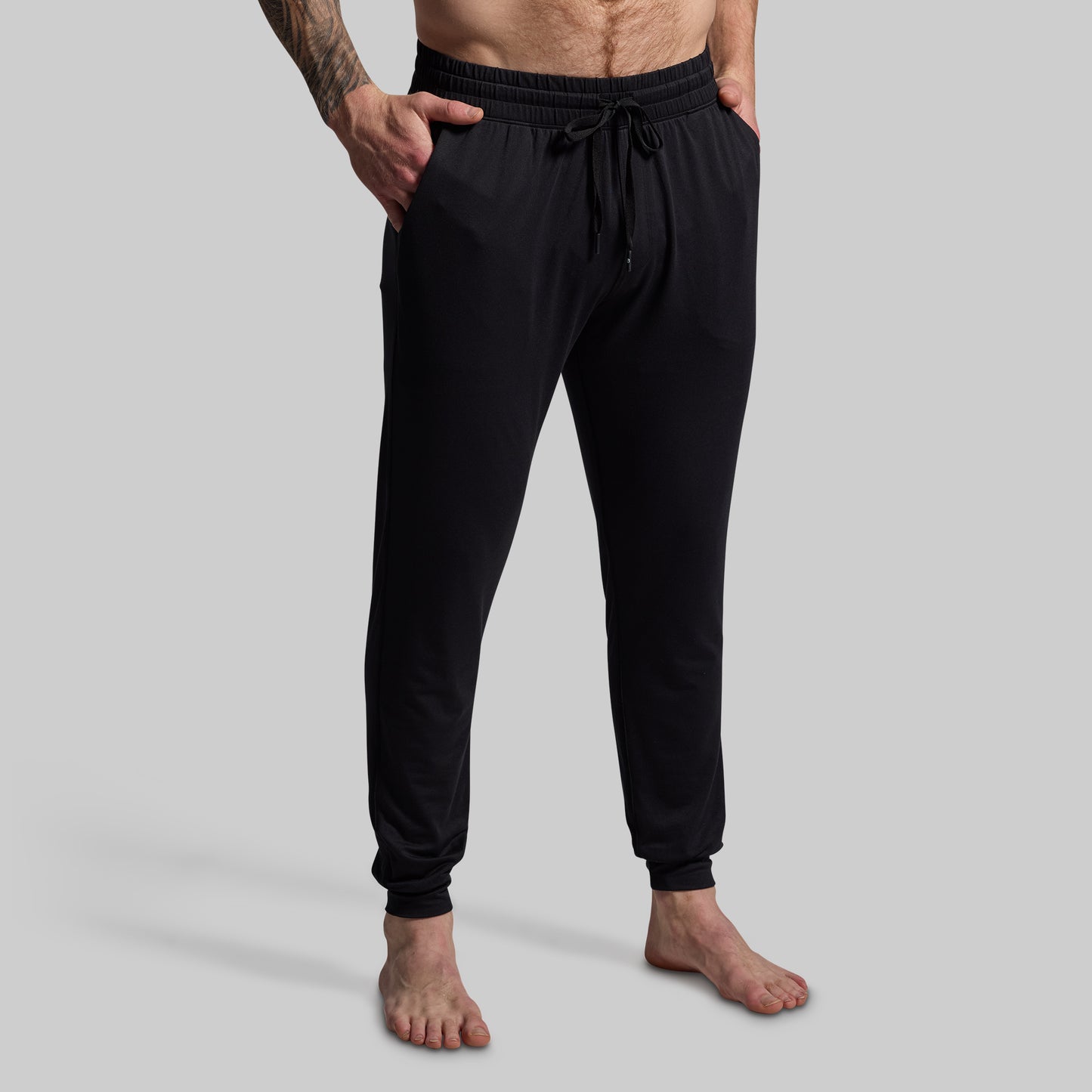 Person wearing black jogger pants on a gray background
