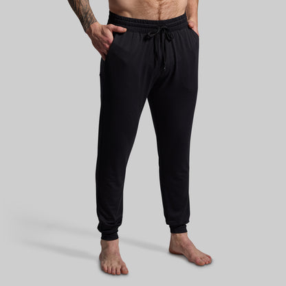 Person wearing black jogger pants on a gray background