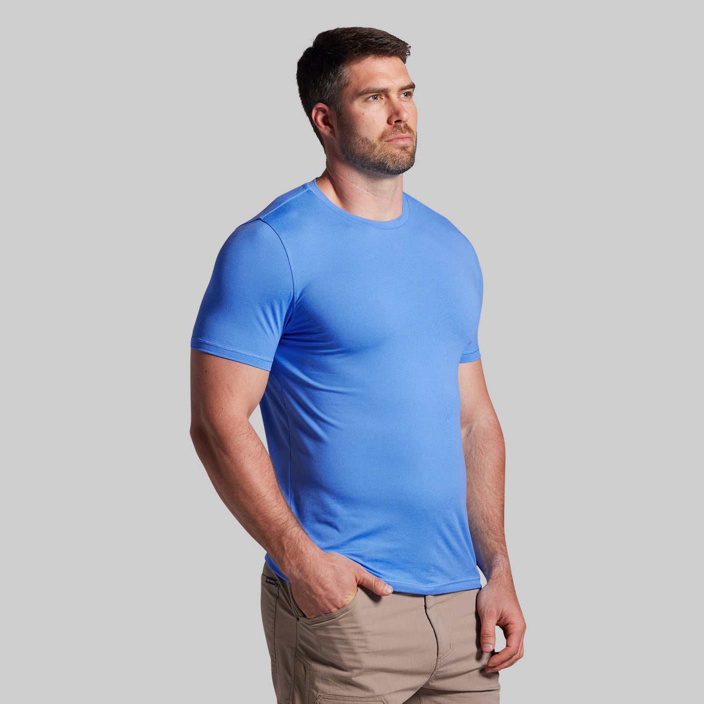 Man wearing a blue t-shirt against a gray background