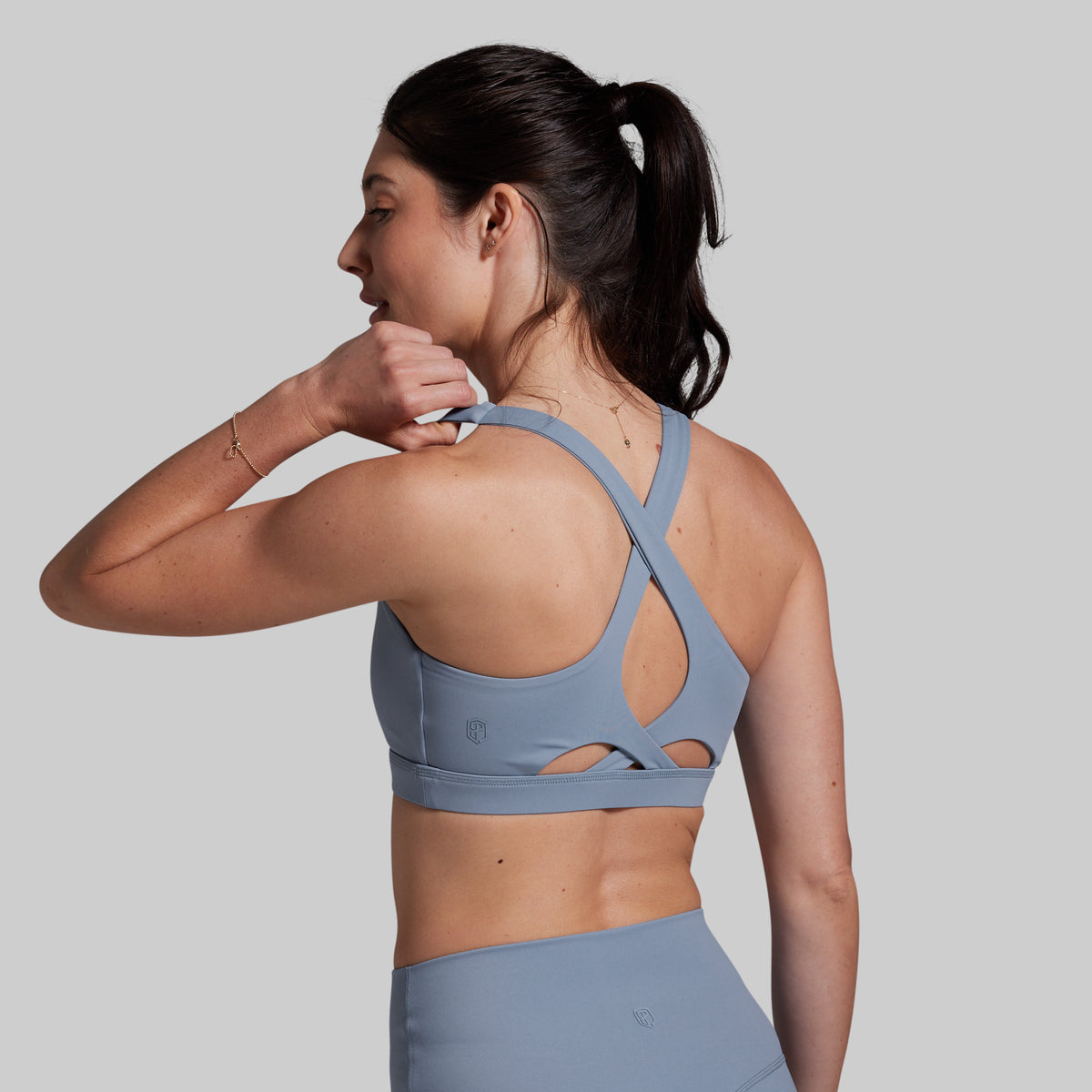 Woman wearing a gray sports bra and shorts on a plain background