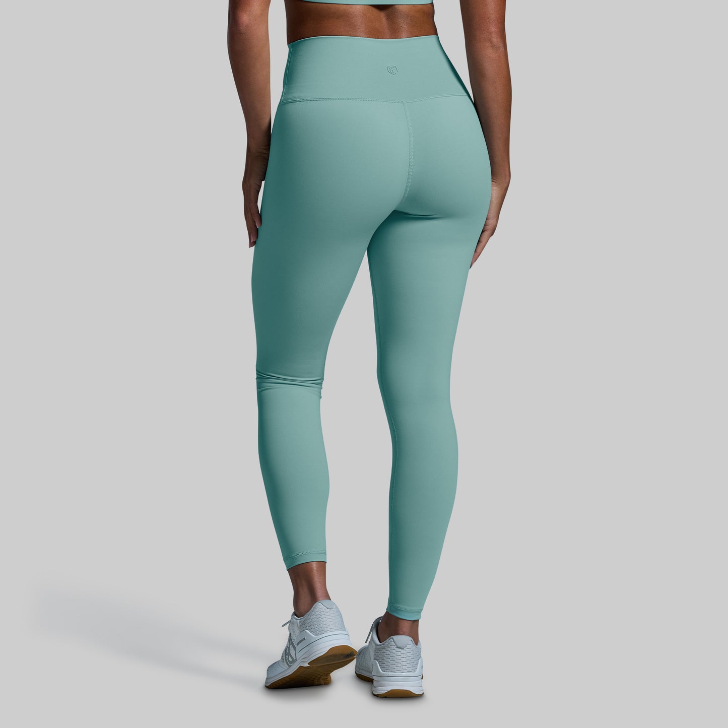 Teal leggings worn by a person on a gray background