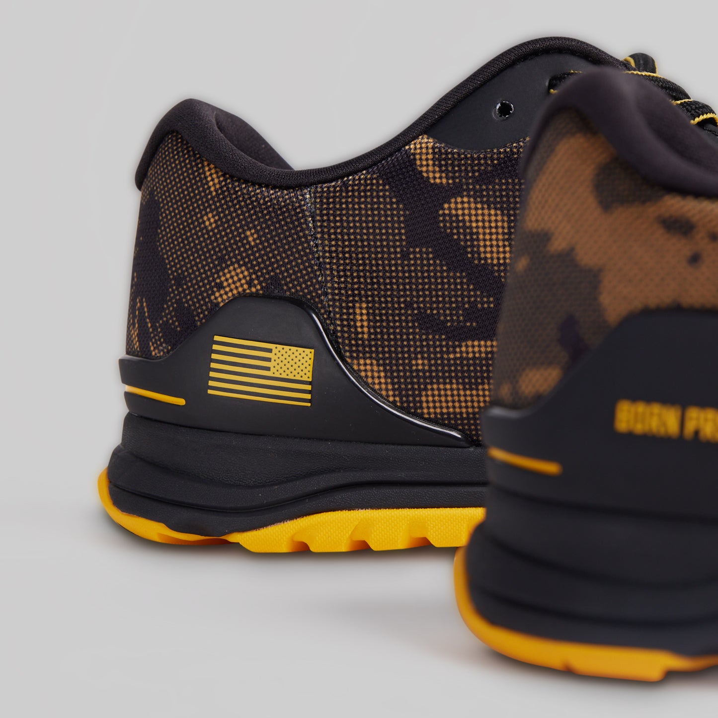 Black and yellow camouflage sneakers with yellow accents on a gray background