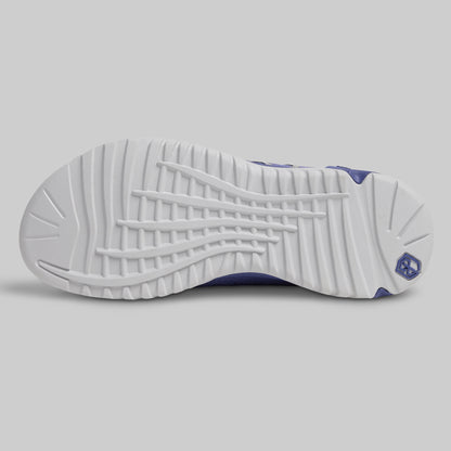 Close-up of a white sneaker sole with purple accents on a light gray background
