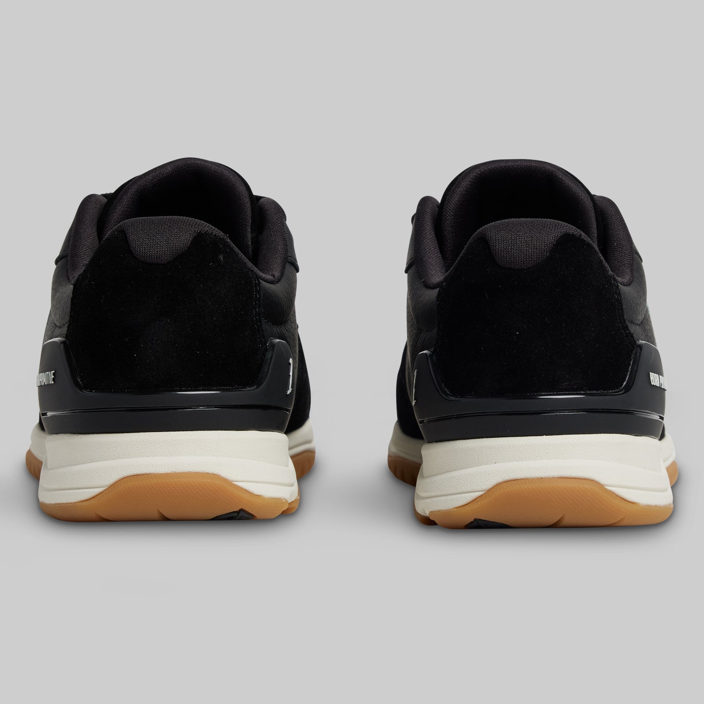 Black sneakers with white soles and brown soles on a gray background