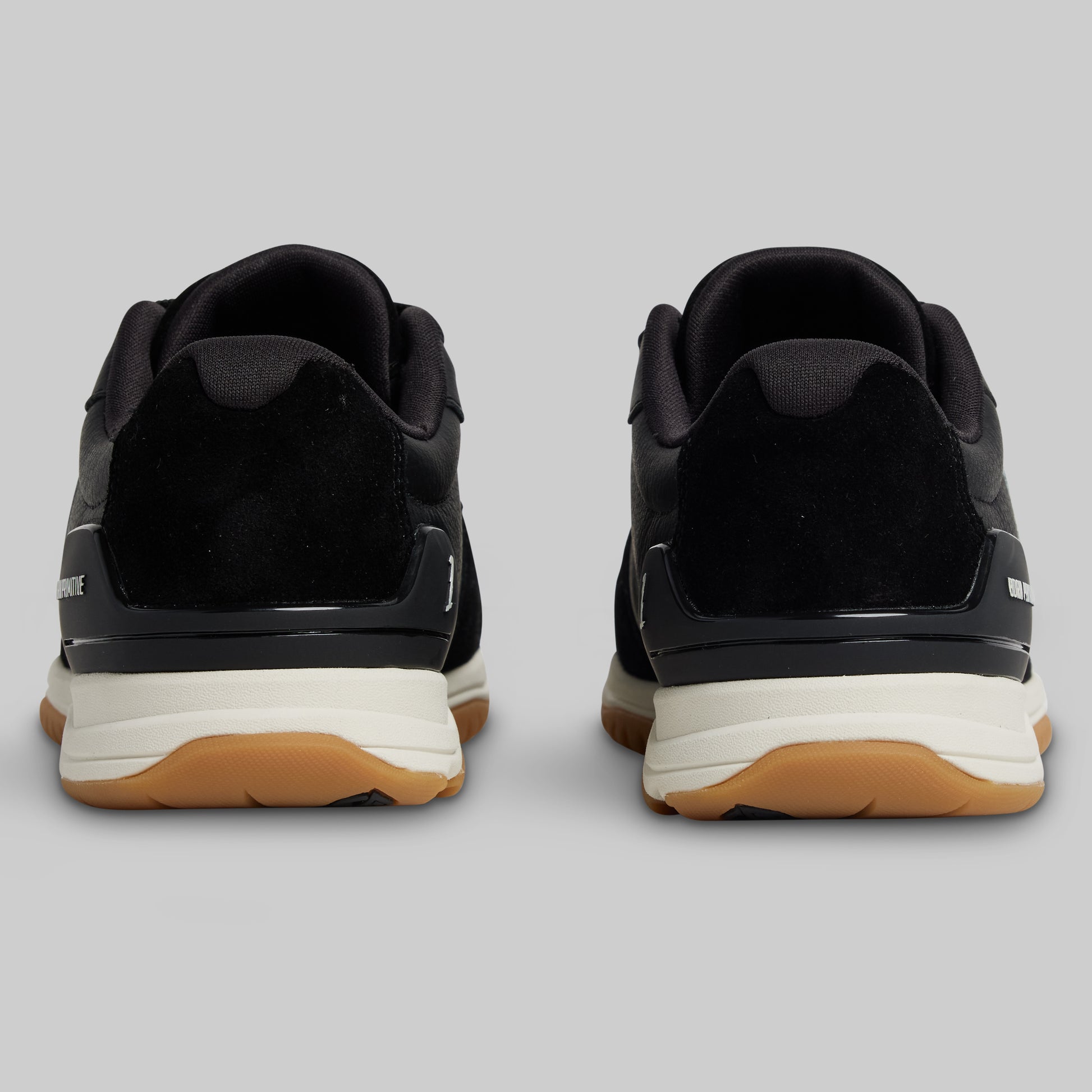 Black sneakers with white soles and brown soles on a gray background