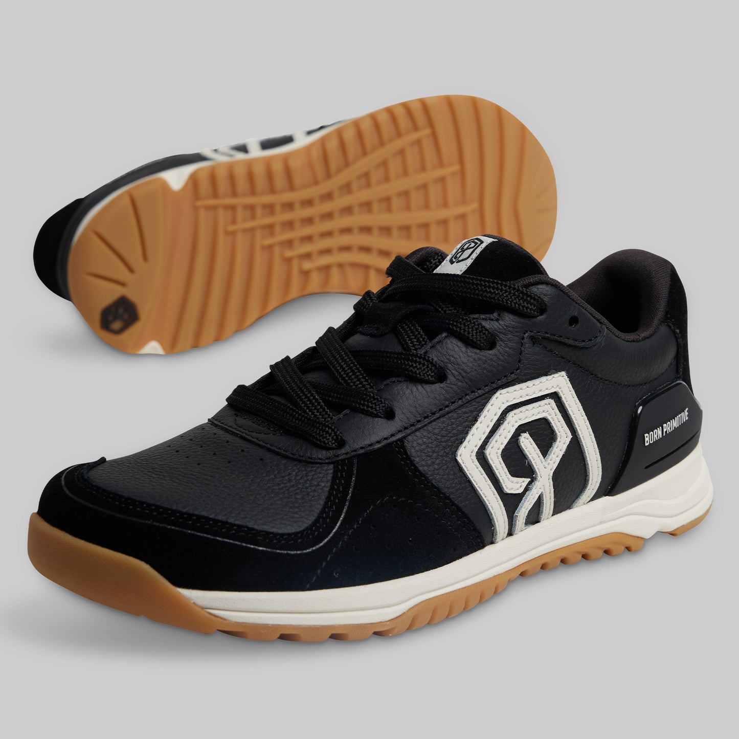Black sneaker with brown sole on a gray background