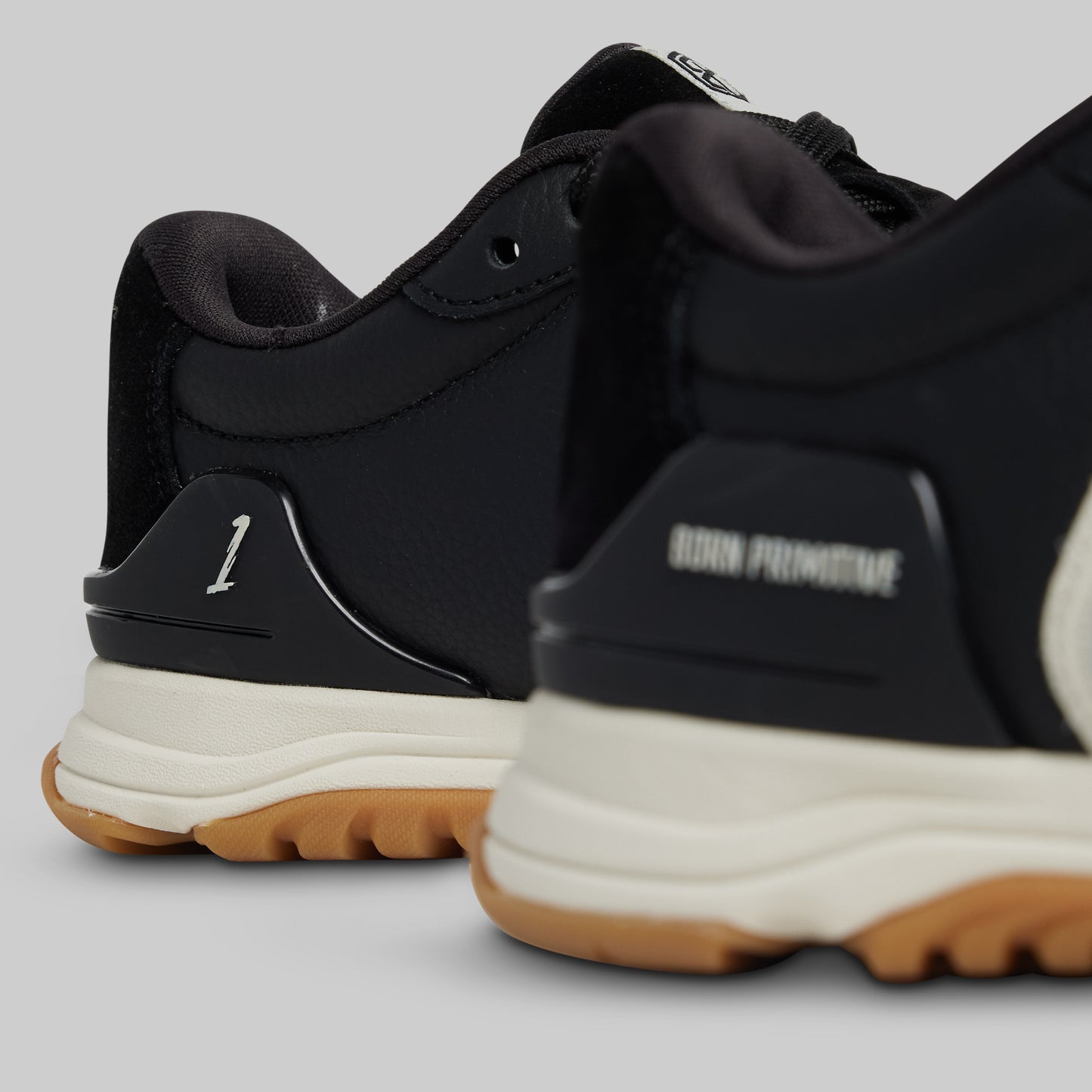 Black sneakers with white soles and brown soles on a light gray background