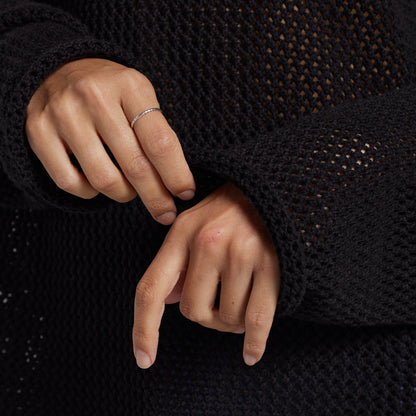 A close-up of a person's hands wearing a black open-knit sweater.