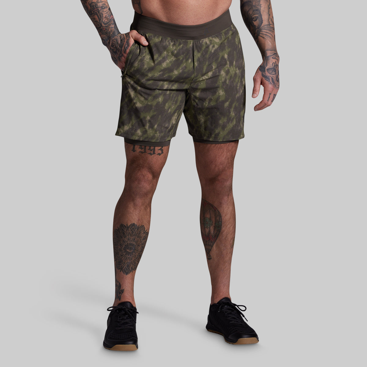 Person wearing camouflage shorts on a plain background