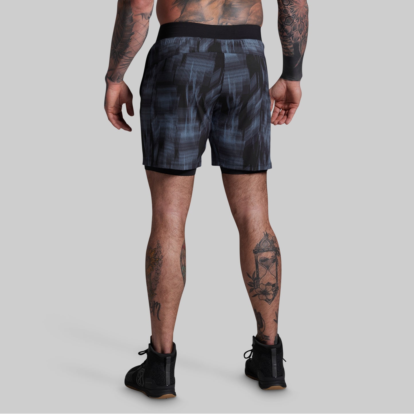 Person wearing black patterned shorts on a gray background