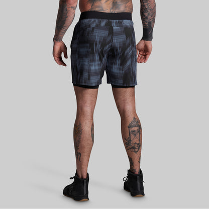 Person wearing black patterned shorts on a gray background