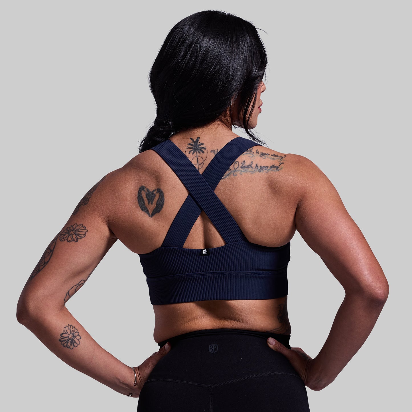Person wearing a navy blue sports bra with criss-cross straps on a plain background