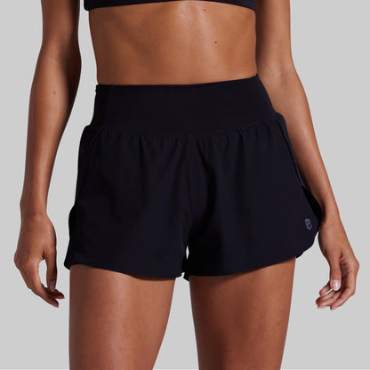 Black athletic shorts worn by a person on a gray background