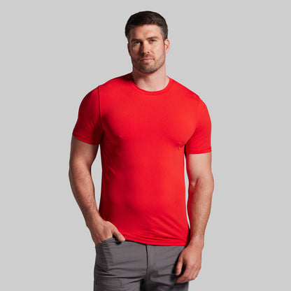 Man wearing a red t-shirt and gray shorts on a light gray background