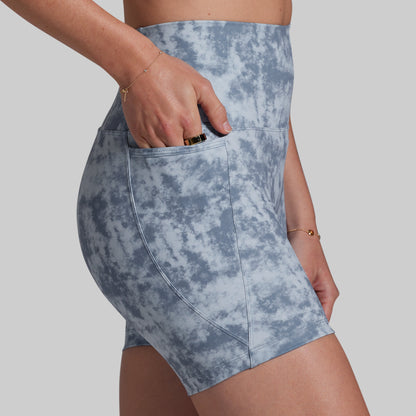 Blue tie-dye shorts worn by a person on a plain background