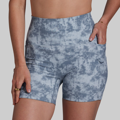 Blue tie-dye shorts worn by a person on a plain background