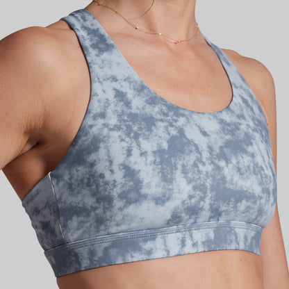 Blue tie-dye sports bra worn by a person on a plain background
