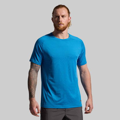 Man wearing a blue t-shirt against a gray background