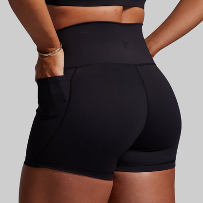 Black athletic shorts worn by a person on a gray background