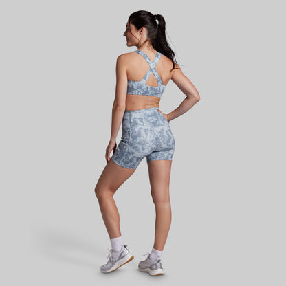Woman wearing a gray tie-dye sports bra and shorts set on a light gray background