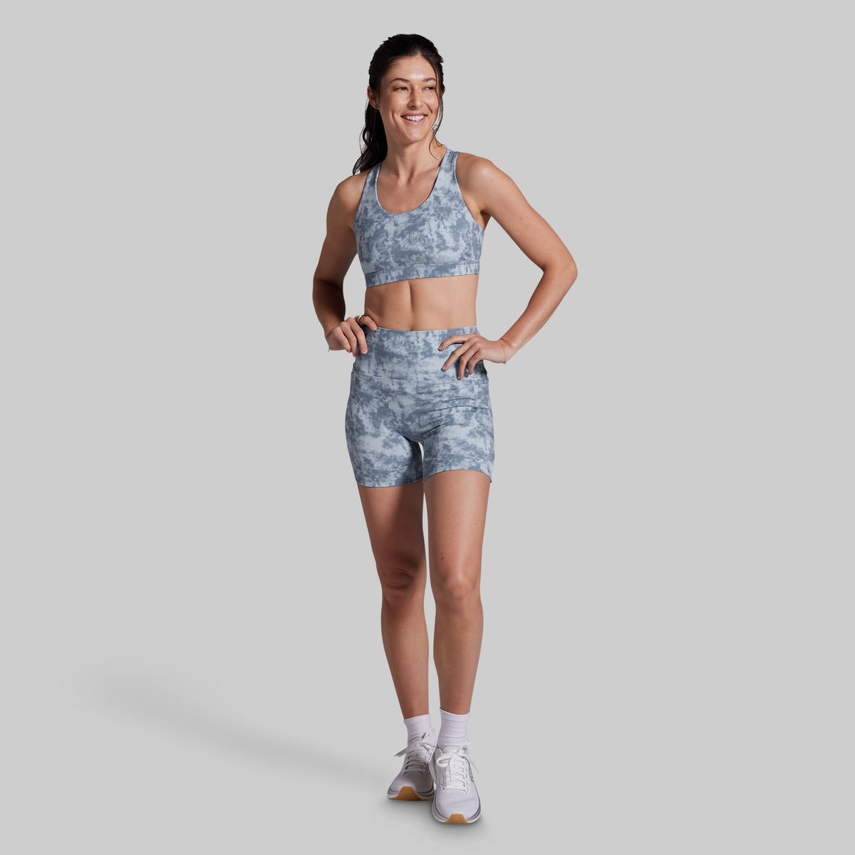 Woman wearing a gray athletic outfit on a light gray background