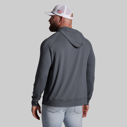 Man wearing a gray hoodie and light blue jeans on a gray background