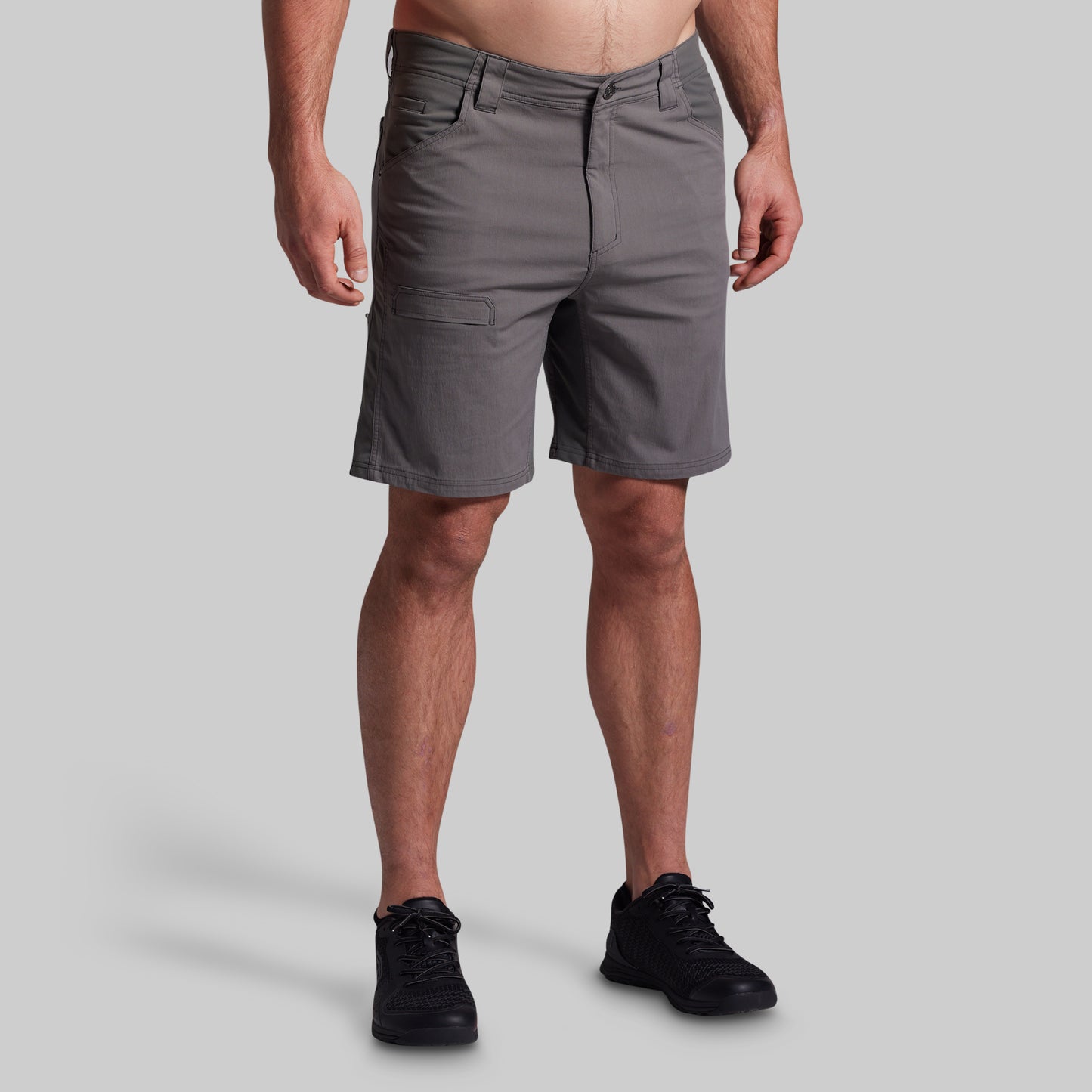 Person wearing gray shorts on a plain background