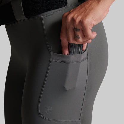 Close-up of a person wearing dark gray leggings with a side pocket, showing a hand reaching into the pocket.