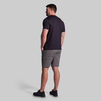 Man wearing a black t-shirt and gray shorts on a light gray background