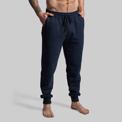 Person wearing navy blue jogger pants on a gray background