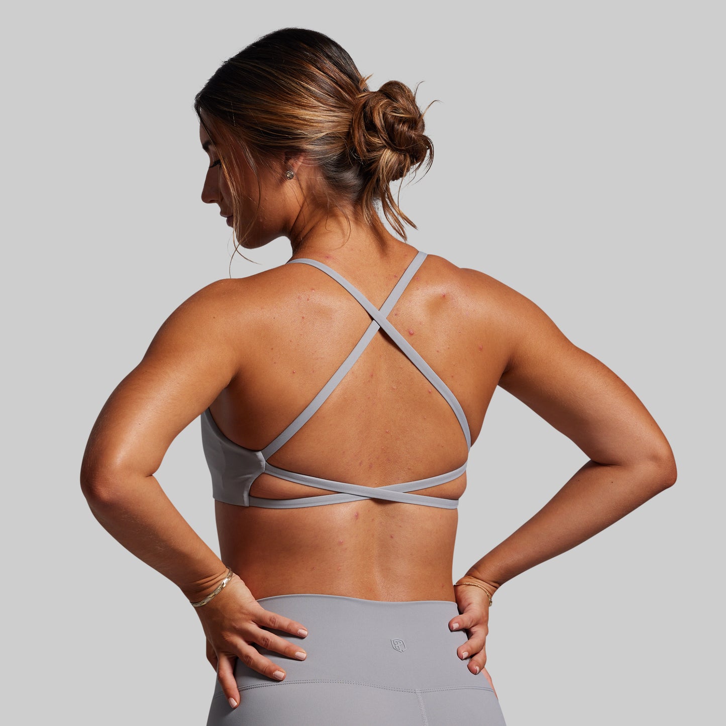 Woman wearing a gray sports bra and leggings on a gray background