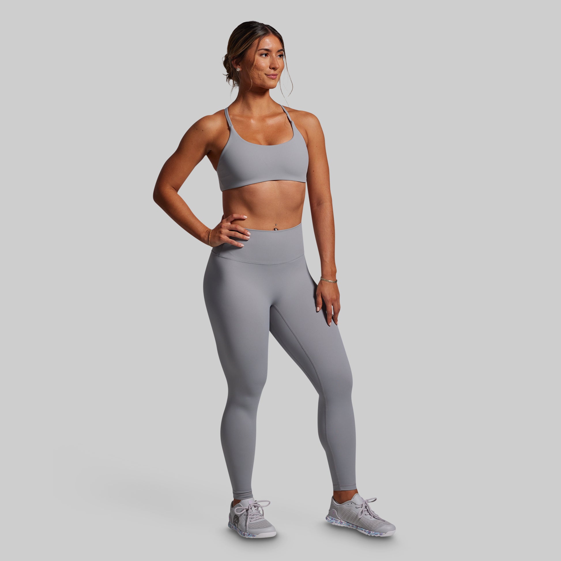 Woman wearing a gray athletic outfit on a plain background