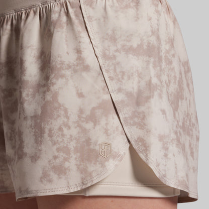 Beige patterned shorts with a brand logo on a light gray background