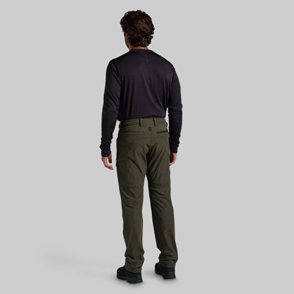 A man viewed from behind wearing a black long-sleeve shirt and olive green cargo pants against a solid gray background.