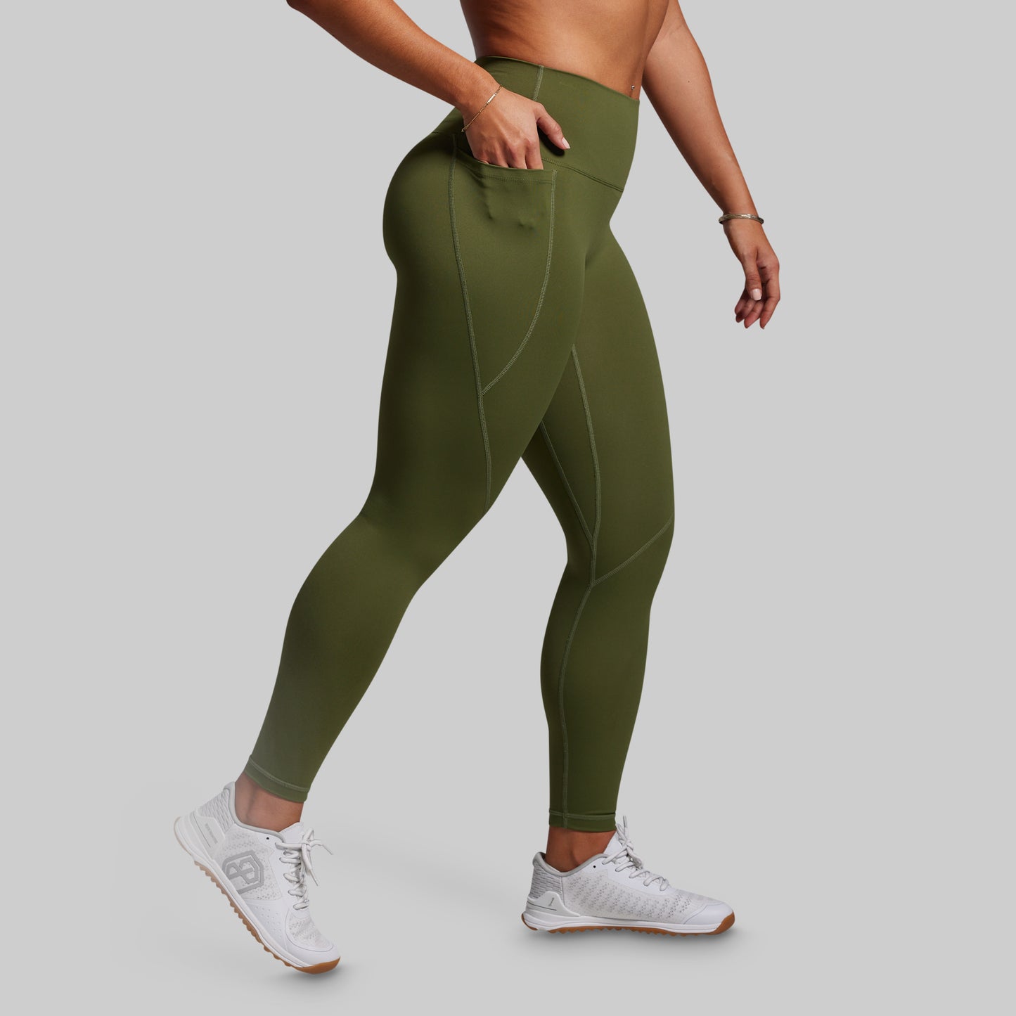 Person wearing olive green leggings on a gray background