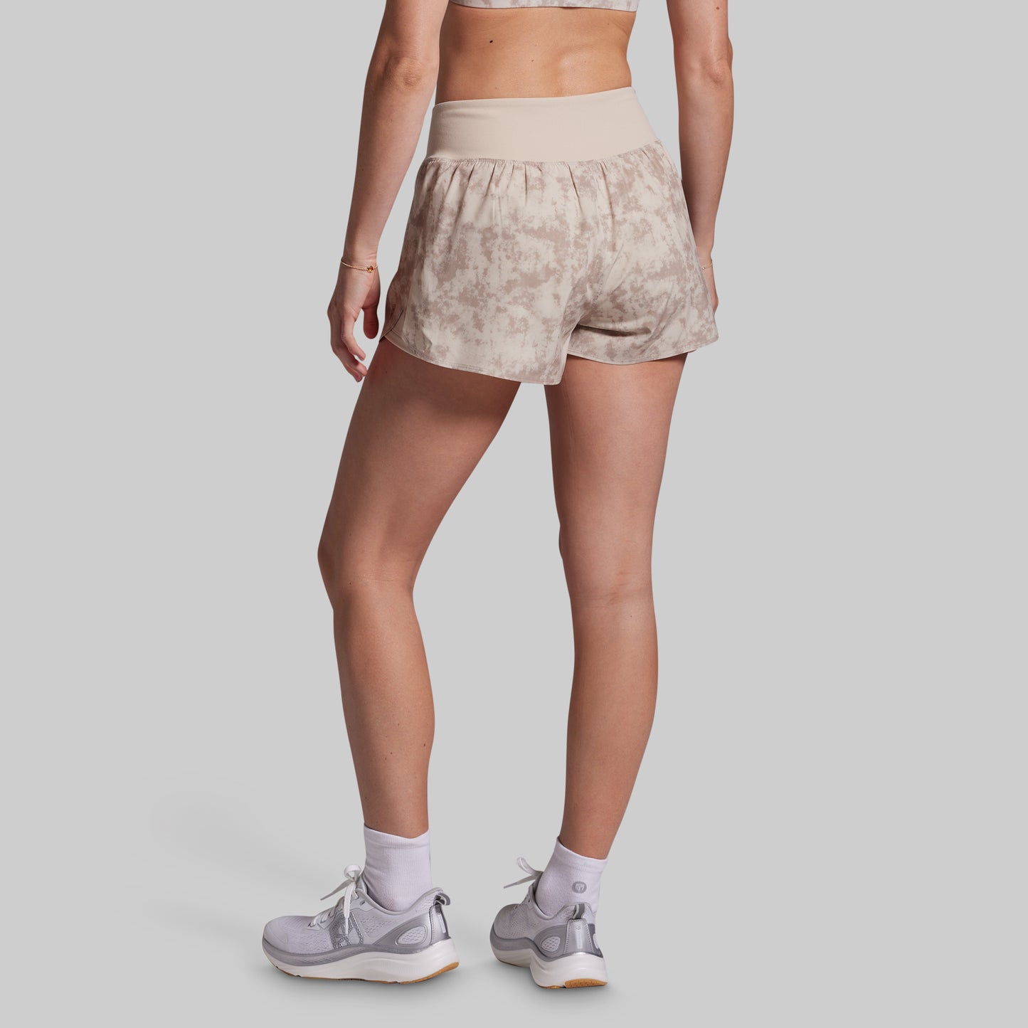 Person wearing beige patterned shorts on a plain background