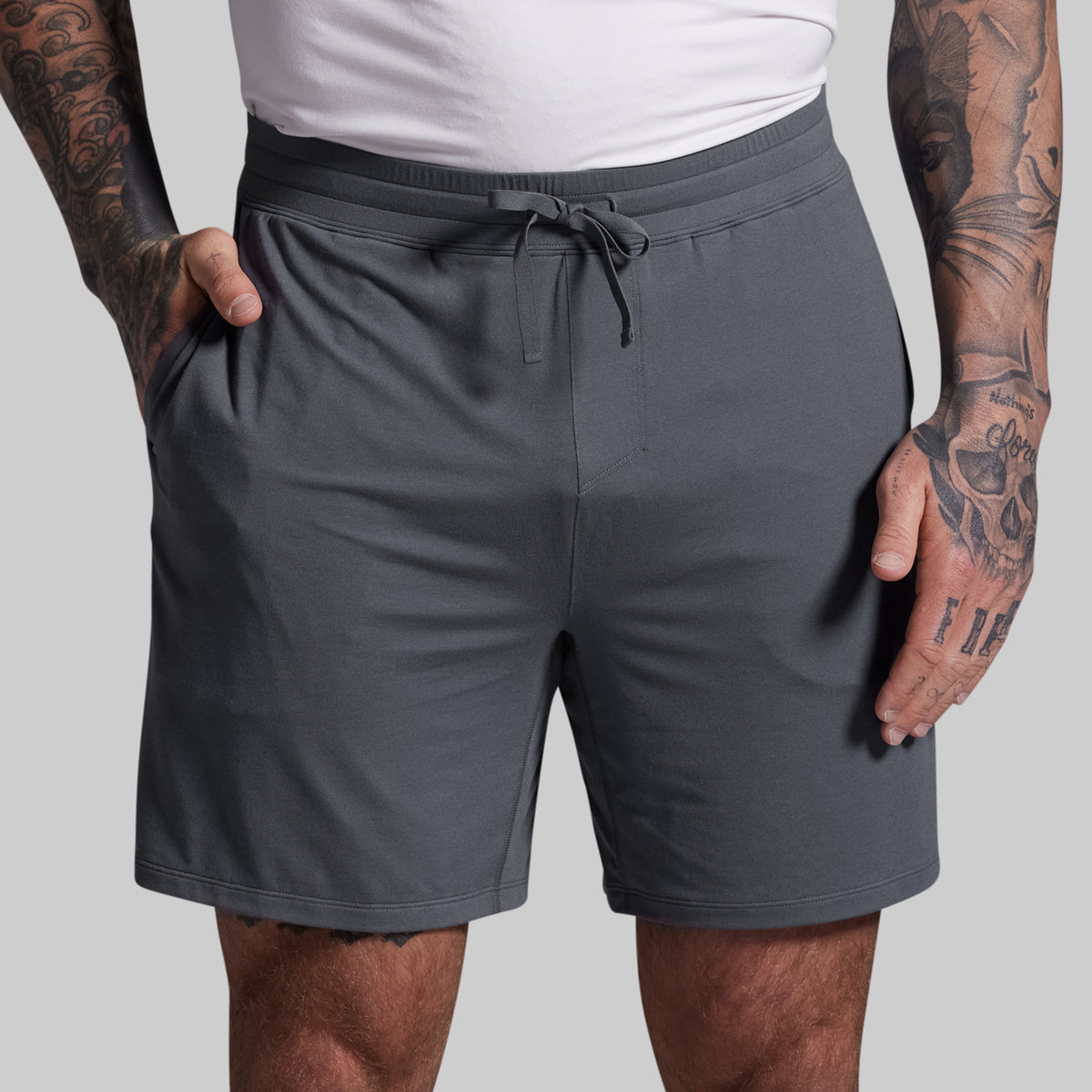 Person wearing gray shorts with a plain background