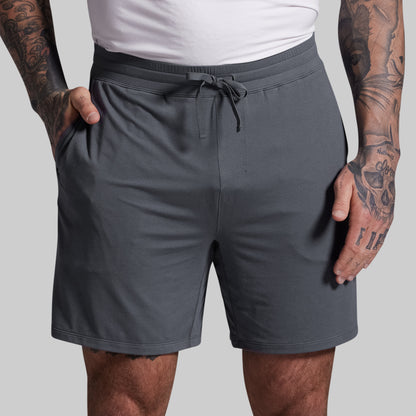 Person wearing gray shorts with a plain background