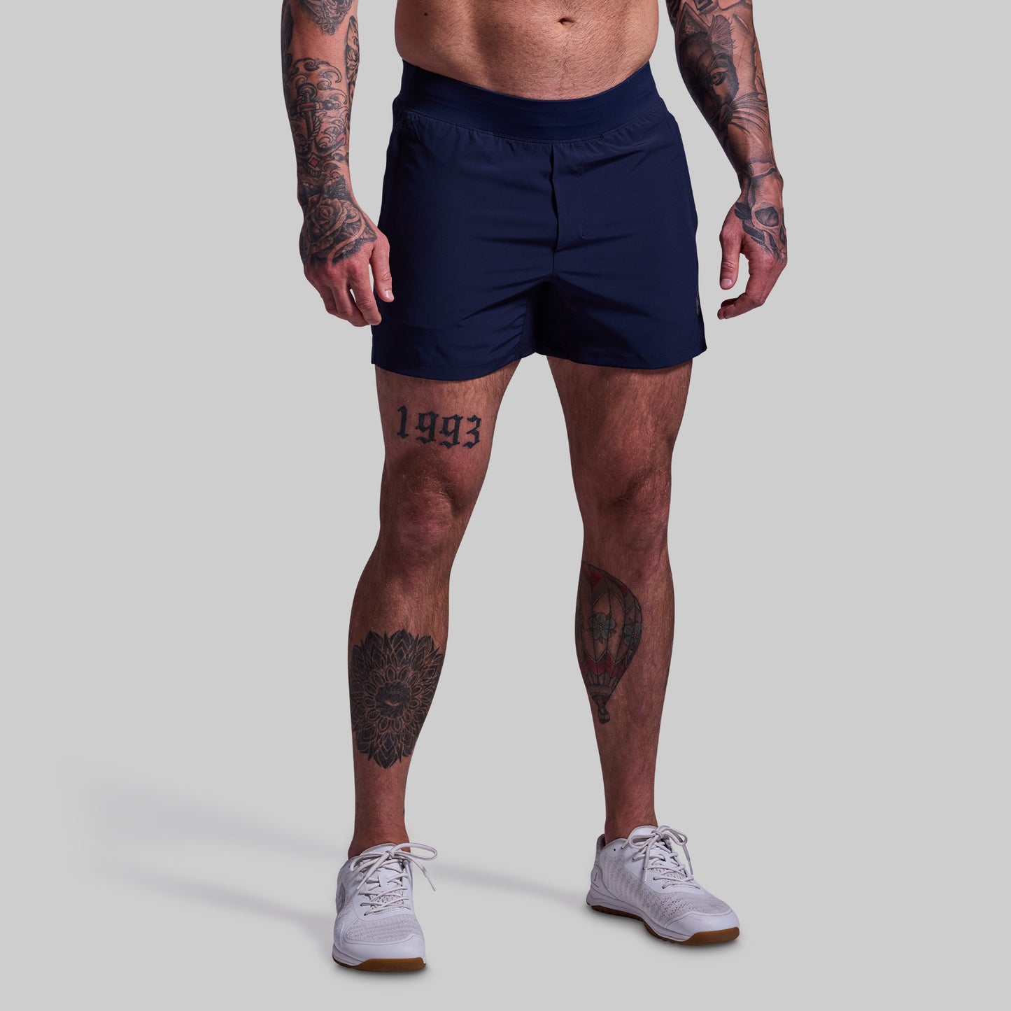 Person wearing navy shorts on a plain background