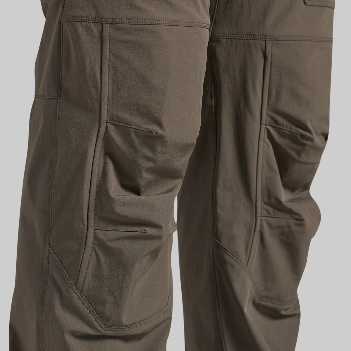 Close-up of grey outdoor cargo pants showing the detailed pocket construction and fabric texture.